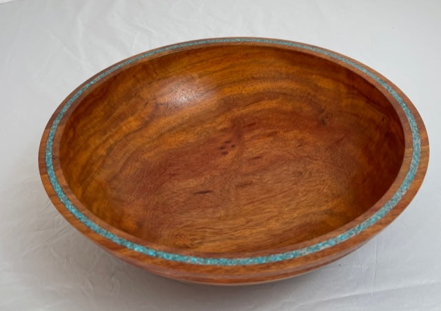 This is a lovely turned bowl made of a honey colored carob wood.  It is inlaid around the rim  of the bowl with Sleeping Beauty turquoise and cold silver.  The wood has a lovely grain.