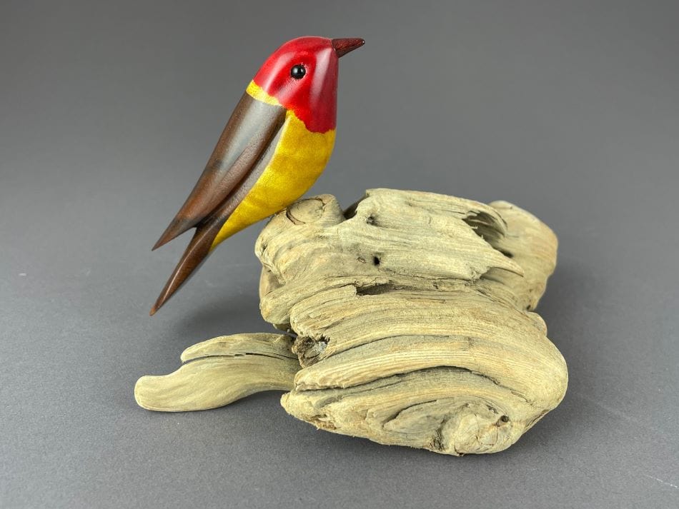 Western Tanager bird sculpture, red head, yellow breast, brown back perched on driftwood base