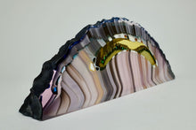 Load image into Gallery viewer, Kiln formed glass sculpture in soft pink, lavender, purple, emerald and gold ribbons of color in an arched shaped piece. The top arched edge is textured with smooth, flat sides and bottom.
